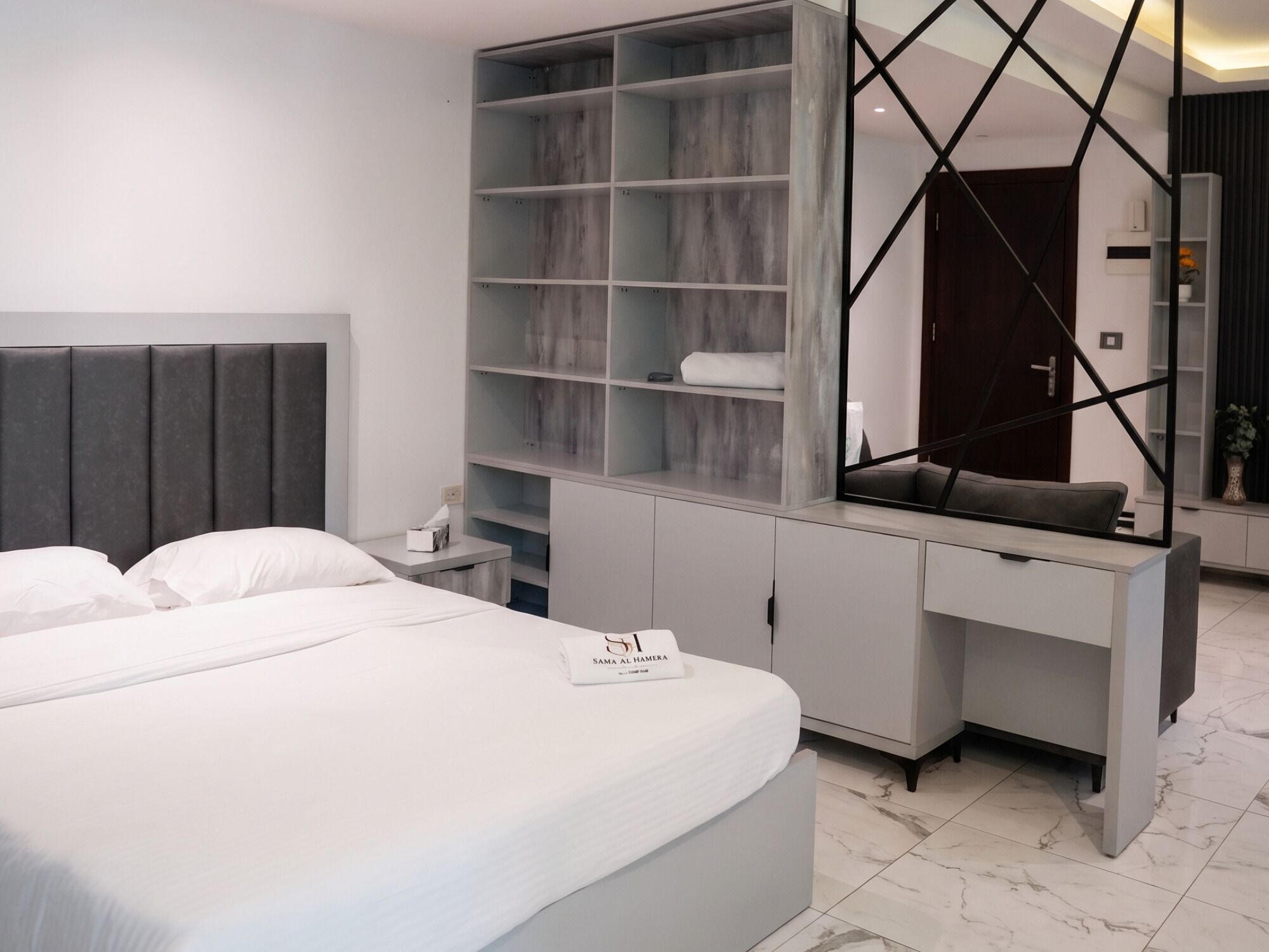 A modern bedroom with a bed, a desk, and a wardrobe.
