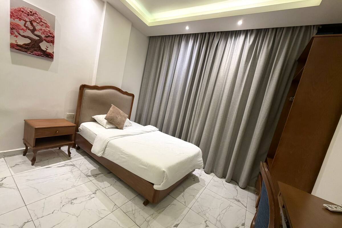 Una camera da letto con un letto, un comodino e un quadro appeso al muro.