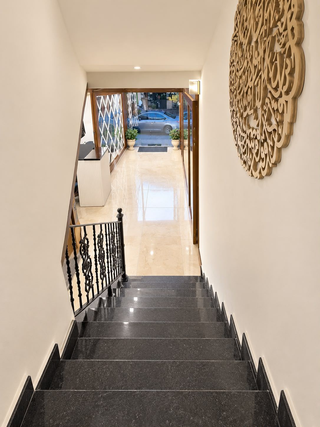 A staircase leading to a lobby with a decorative wall and a view of the street outside.