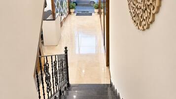 A staircase leading to a lobby with a decorative wall and a view of the street outside.