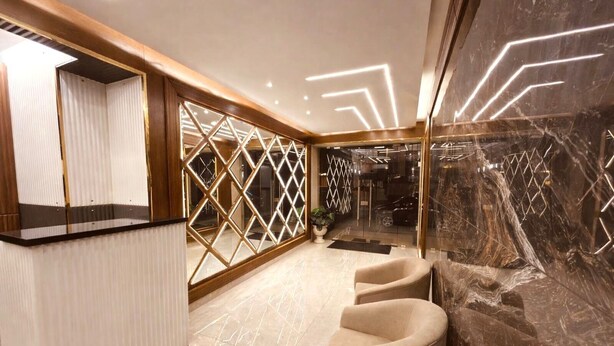 A modern reception area with a marble wall, a reception desk, and a seating area with chairs. - Sama Al Hamra Furnished Apartments (Beirut)