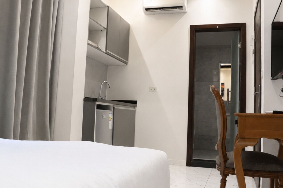 Une chambre d’hôtel équipée d’un lit, d’un bureau, d’une chaise, d’une kitchenette et d’un appareil de climatisation.