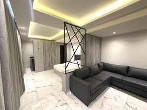 A modern living room with a sectional sofa, a marble floor, and a geometric decorative element. - Sama Al Hamra Furnished Apartments (Beirut)