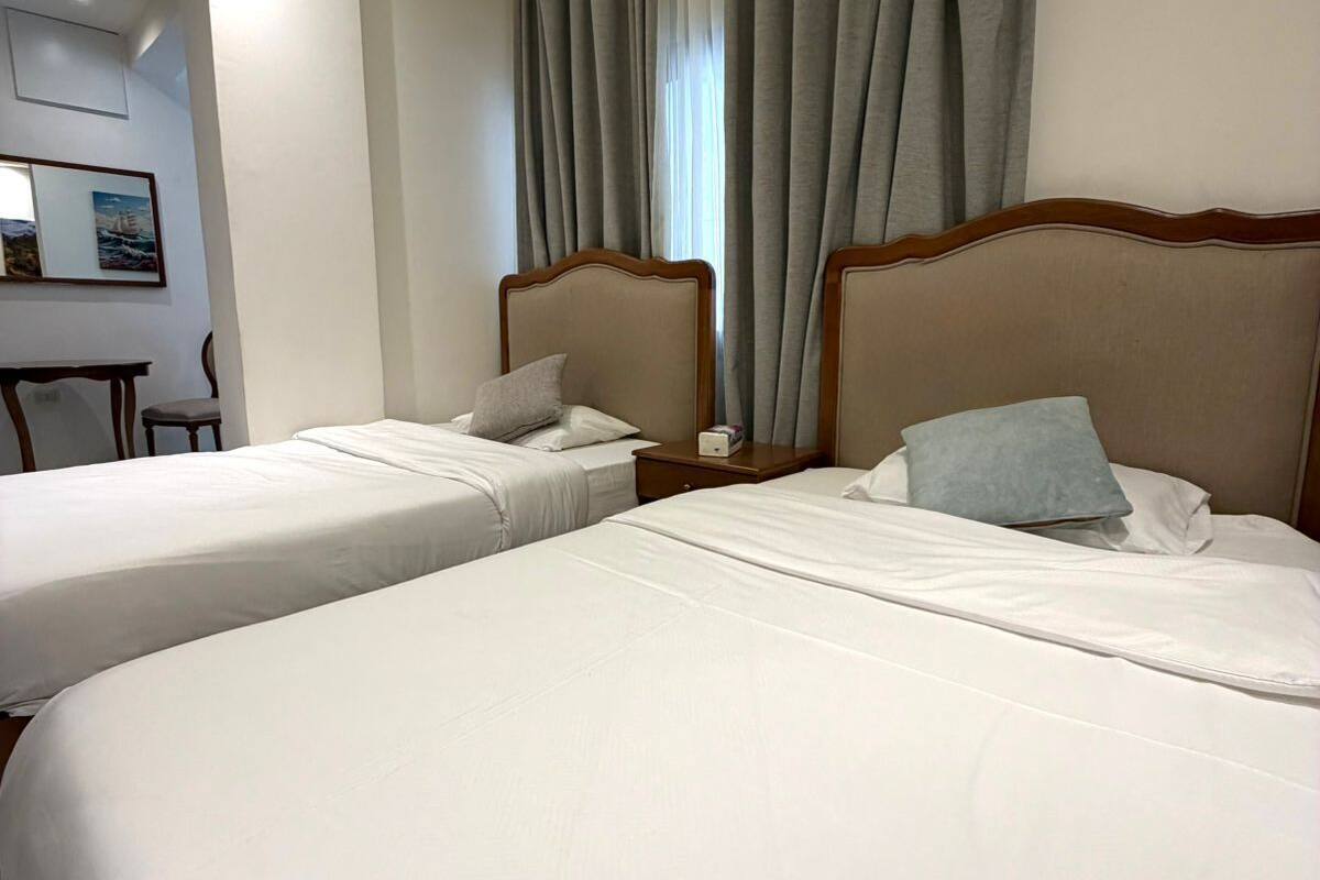 Una camera d'albergo con due letti, una scrivania e una sedia.
