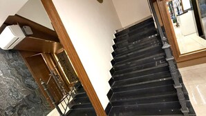 A modern staircase with black steps and wooden railings, leading to a landing with a blue accent wall and a decorative wall piece. - Sama Al Hamra Furnished Apartments (Beirut)