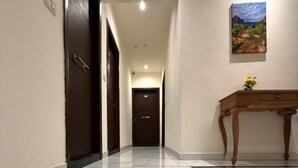 A hallway with a marble floor, a wooden table with a vase of flowers, and a painting on the wall. - Sama Al Hamra Furnished Apartments (Beirut)