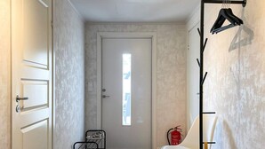 A hallway with a door, a shoe rack, a chair, a fire extinguisher, and a coat rack. - 4 Star Holiday Home in Gotlands Tofta (Gotlands Tofta)