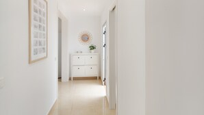 A hallway with a white wall, a framed picture, a white cabinet with drawers, and a round mirror on the wall. - Vacation Apartment 'Nature and Calm Escape' with Mountain View and Wi-Fi (Los Silos)