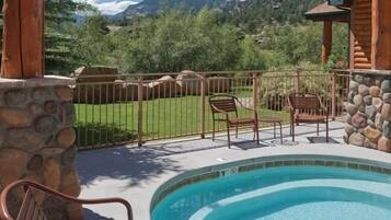 Une pergola en bois avec une piscine, un mur en pierre et des chaises.