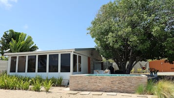 Une maison avec une piscine, un grand arbre et un espace barbecue.