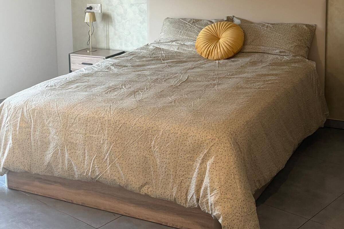 A bedroom with a bed, a nightstand, and a lamp.