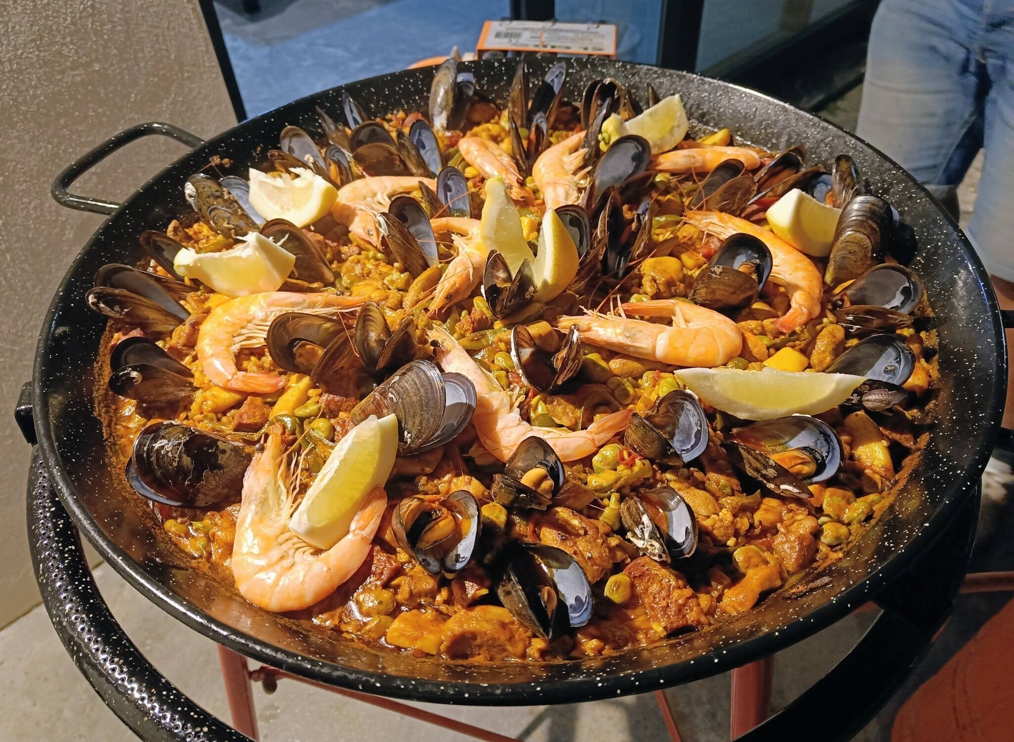 Paella gran de marisc amb gambes, musclos i trossos de llimona.