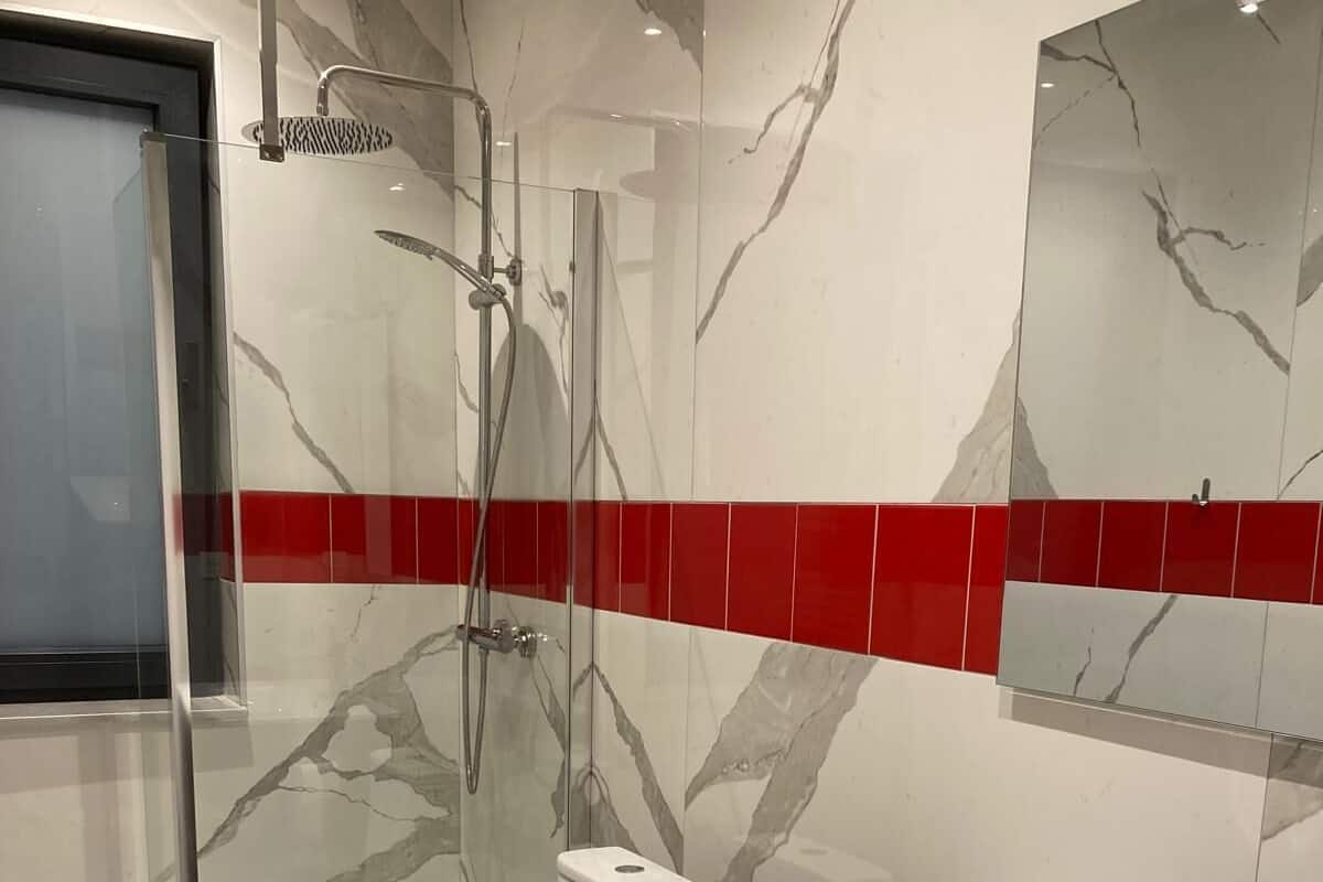 A modern bathroom with a glass shower enclosure, a white sink, and a wooden vanity.