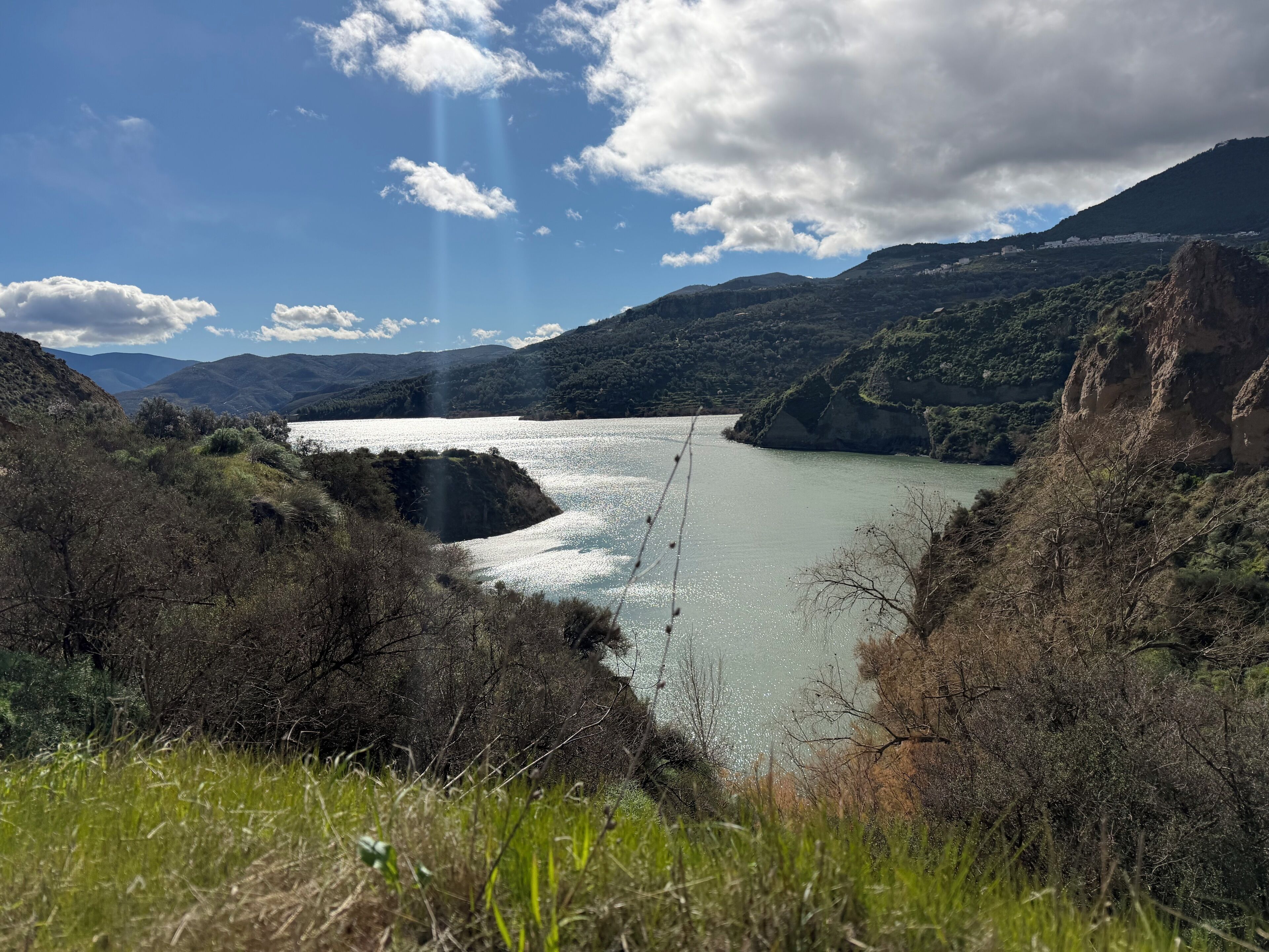 Um vale fluvial com montanhas ao fundo e um céu claro.