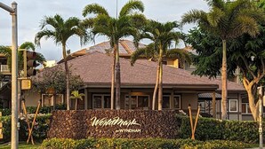 Un hôtel dont l’entrée est marquée par un mur de pierre, agrémenté de palmiers et d’une enseigne indiquant « Worldmark by Wyndham ».