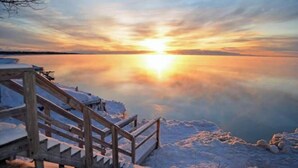 A wooden staircase leading to a platform by a calm body of water during sunset.