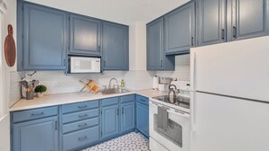 Una cucina con mobili blu, un forno a microonde bianco, un lavello e una stufa.