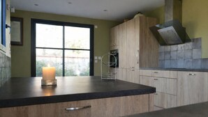 Een moderne keuken met houten kastjes, een zwart aanrechtblad en een brandende kaars.