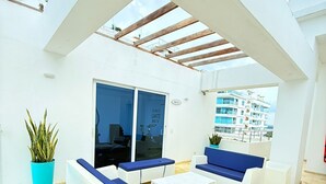 An outdoor seating area with white sofas and blue cushions, a coffee table, and potted plants. - Apartamento 504 vista al mar  (Cartagena)