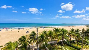 A beach with palm trees, umbrellas, and a clear sky. - Apartamento 504 vista al mar  (Cartagena)
