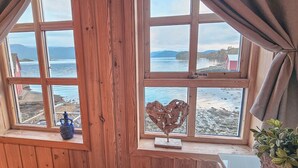 Una habitación con paredes de madera y grandes ventanales con vistas a la playa.
