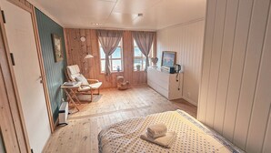 Una habitación con cama, una silla, una mesa, un calentador y una ventana con cortinas.