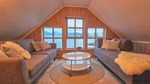 Acogedor dormitorio en ático con dos sofás orientados hacia un ventanal con vistas a una masa de agua.