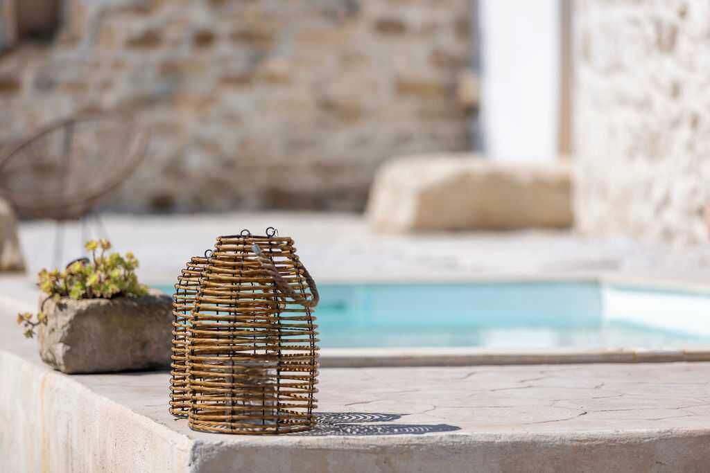 A wicker basket on a stone ledge near a pool with a stone wall in the background.
