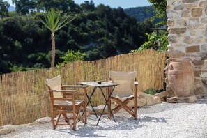 Un área de estar al aire libre con una mesa, sillas, una palmera y un muro de piedra.