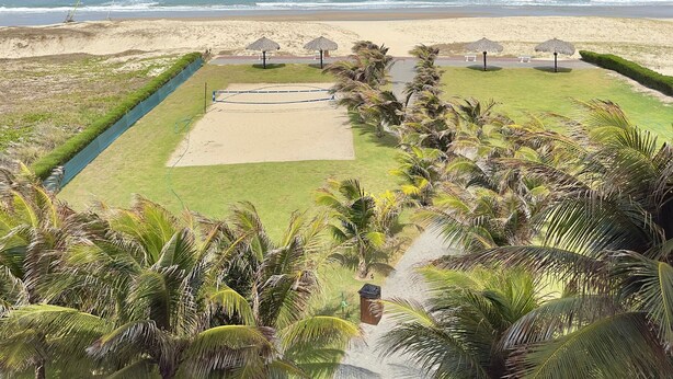 Vista de la playa con un camino que lleva a un área de descanso con sombrillas.