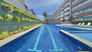 Una piscina con una línea de agua azul cristalina, rodeada de edificios con balcones y plantas en macetas.