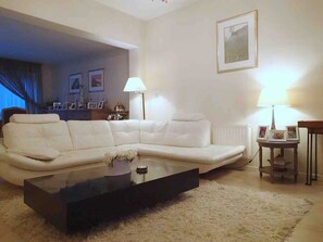 Un salon avec un canapé blanc, une table basse en verre et une lampe.