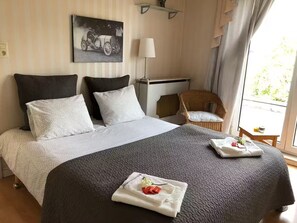 Une chambre d’hôtel avec un grand lit, une chaise, un bureau et une fenêtre avec des rideaux.