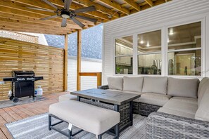 Eine überdachte Terrasse mit Grill, Sitzgelegenheit und Blick ins Haus.