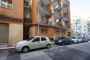 A multi-story residential building with balconies, parked cars, and a closed shop door. - Bengasi Central Loft – Stile, Comfort e Serenità (Bari)