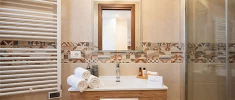 A bathroom with a white sink, wooden vanity, towel rack, and patterned tiles.