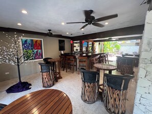 Een bar met houten meubels, plafondventilatoren en kunstwerken aan de muur.