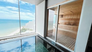 Et højt beliggende hotelværelse med stor balkon, glasgulv og udsigt over strand og hav.
