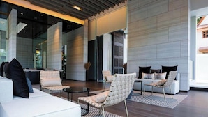 En moderne lobby med højt til loftet, store vinduer og et siddeområde med sofaer og stole.
