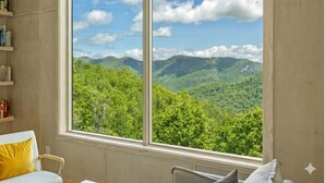 A room with a large window offering a view of a mountainous landscape.