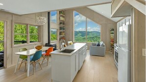 A modern kitchen with a large island, built-in shelves, and a view of the mountains.