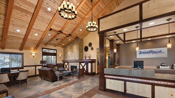 A spacious lobby with a stone fireplace, wooden ceiling beams, and a reception desk with a 'Wordmark' sign.