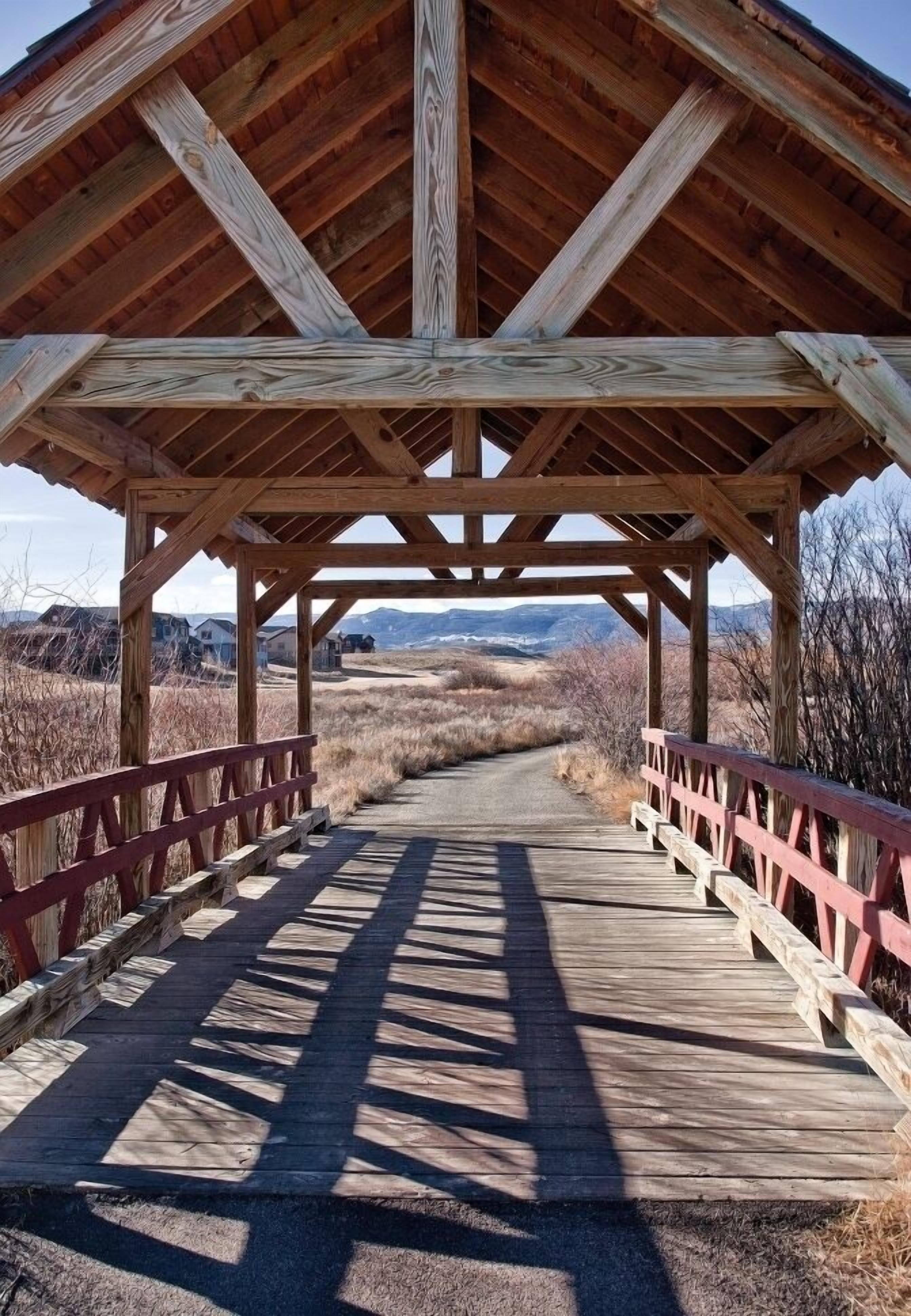 A wooden covered bridge with a simple, open design and a clear view of the surrounding landscape.