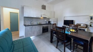 A compact kitchen with a dining area, a sofa, and a television. - Casa Ulisse with large garden and parking (Campo nell'Elba)