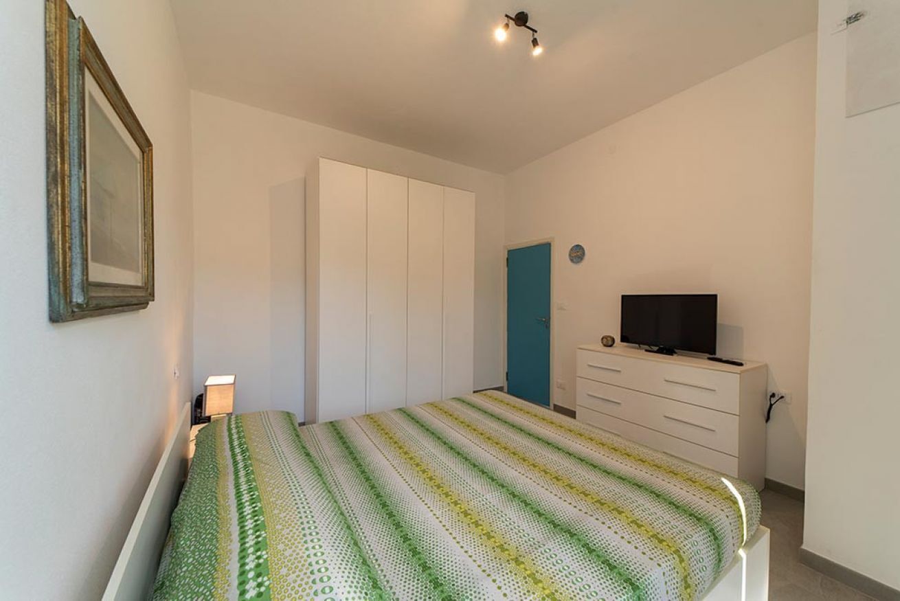 Un dormitorio con cama, armario, televisor y puerta.
