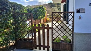 A gated entrance with a wooden fence, a white building with a balcony, and a sign indicating a cat-friendly area. - Casa Ulisse with large garden and parking (Campo nell'Elba)