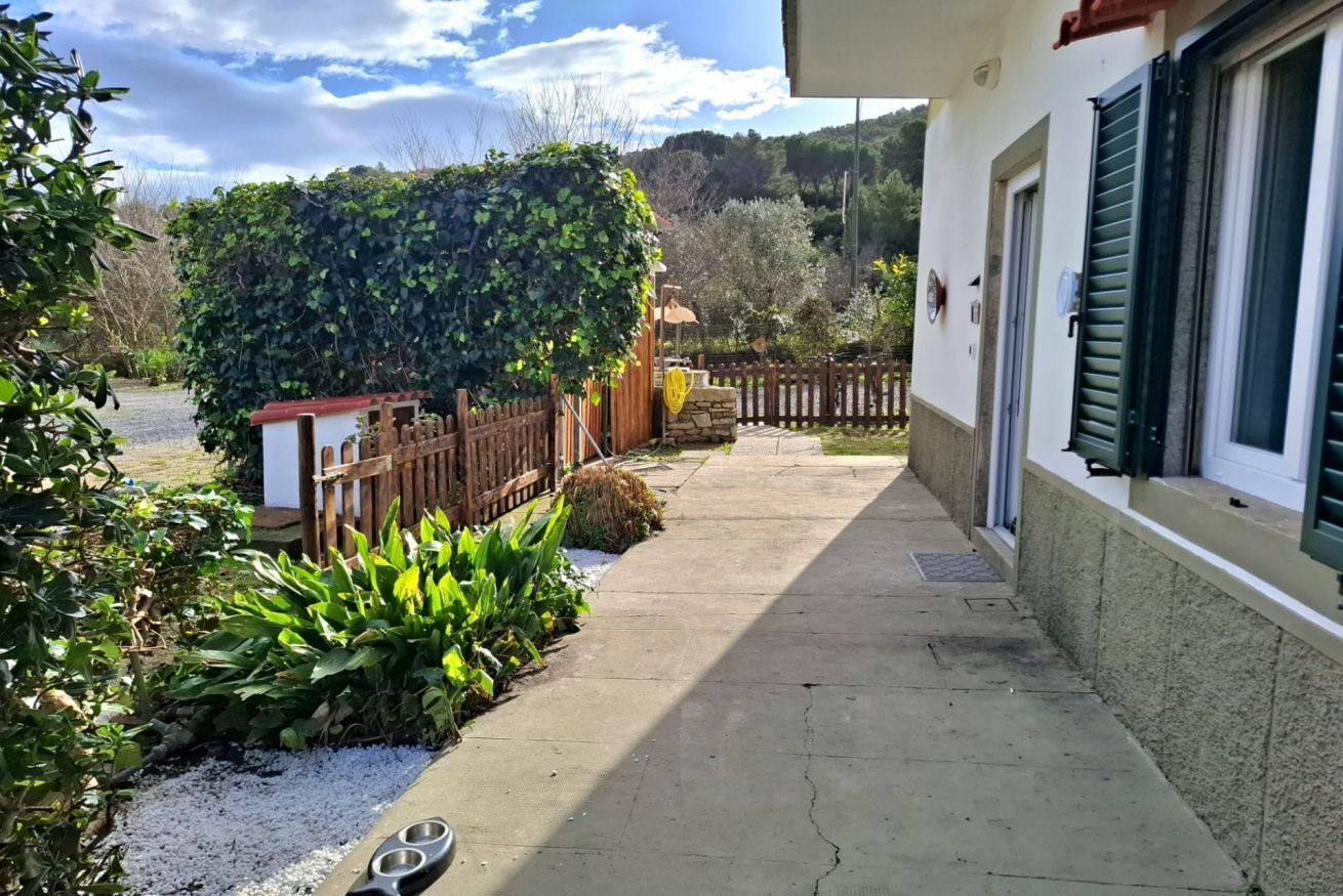 A pathway leading to a building with a wooden fence and a stone wall.