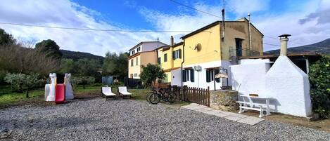 A two-story building with a gravel driveway, a bicycle, and outdoor seating.