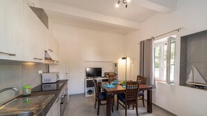 A modern kitchen with a dining area, a TV, and a sailboat decoration. - Casa Ulisse with large garden and parking (Campo nell'Elba)