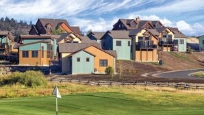 A golf course with a flagstick in the foreground and houses in the background.